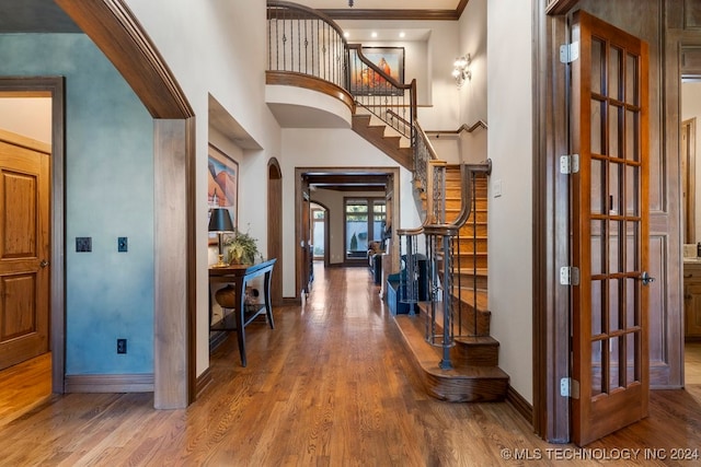 foyer entrance with hardwood / wood-style floors, a high ceiling, and ornamental molding