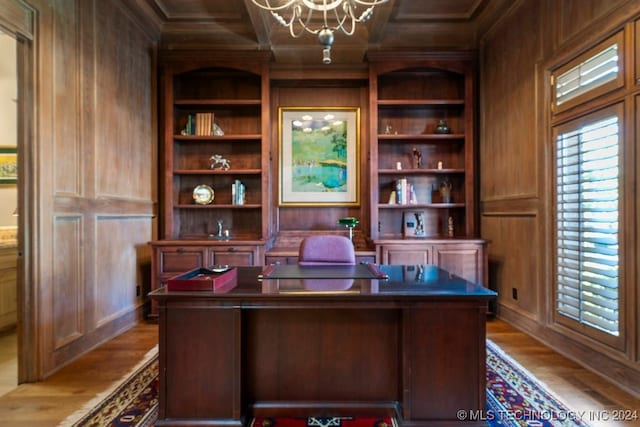 home office featuring built in features, wood-type flooring, an inviting chandelier, and wood walls