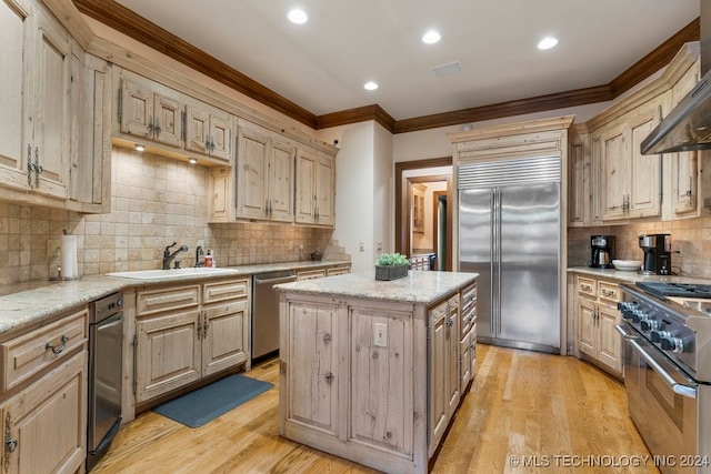 kitchen with a center island, high quality appliances, crown molding, sink, and light wood-type flooring