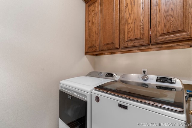 laundry area with washer and clothes dryer and cabinets