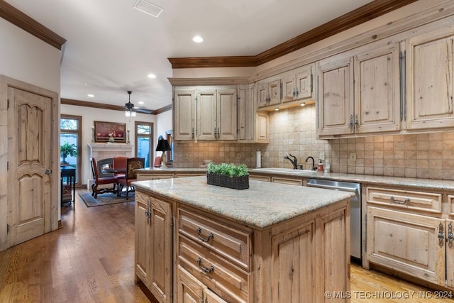 kitchen with light wood-type flooring, stainless steel dishwasher, ceiling fan, crown molding, and a center island