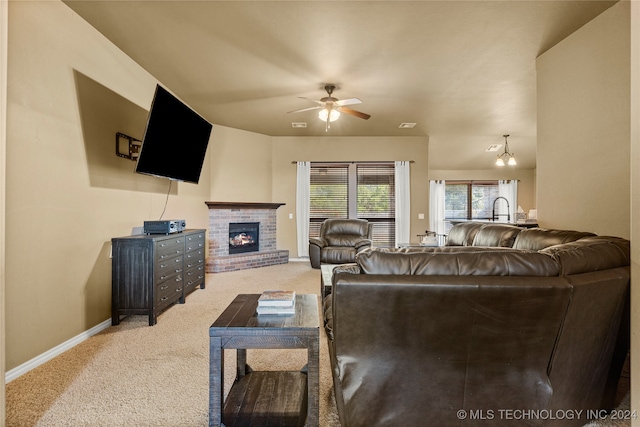 carpeted living room featuring a fireplace and ceiling fan with notable chandelier