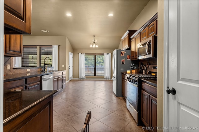 kitchen featuring appliances with stainless steel finishes, sink, light tile patterned flooring, backsplash, and a notable chandelier