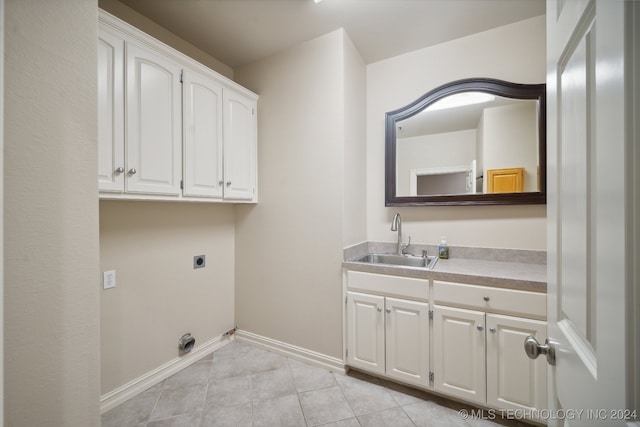 clothes washing area with hookup for an electric dryer, light tile patterned floors, cabinets, and sink