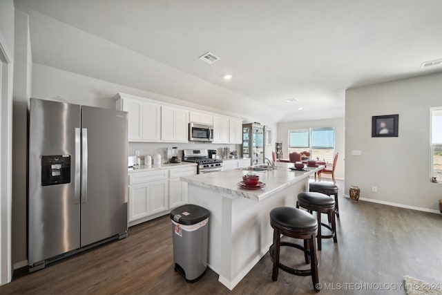 kitchen featuring a kitchen island with sink, a breakfast bar, white cabinetry, appliances with stainless steel finishes, and dark hardwood / wood-style flooring