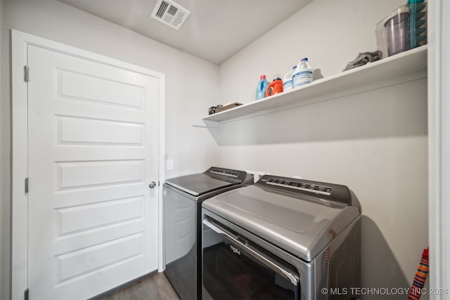 clothes washing area with washing machine and clothes dryer and hardwood / wood-style flooring