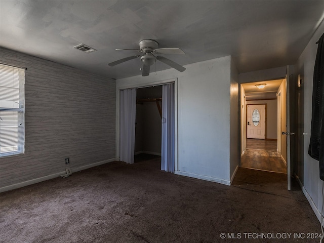 unfurnished bedroom with ceiling fan, a closet, and dark colored carpet