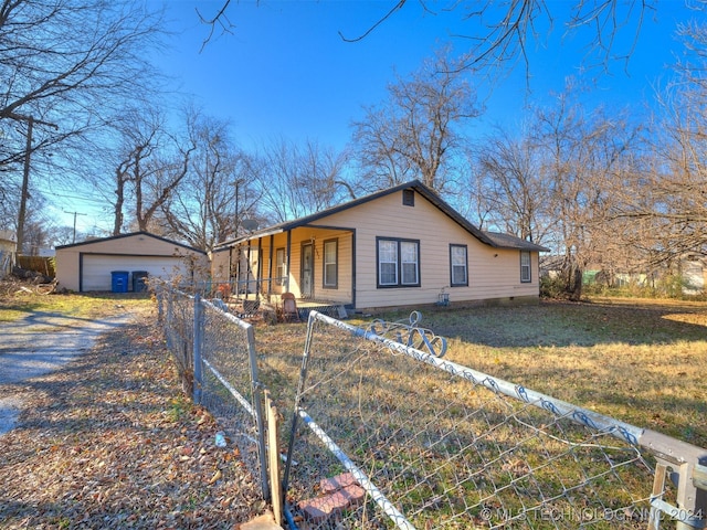 ranch-style home featuring covered porch, an outbuilding, a garage, and a front lawn