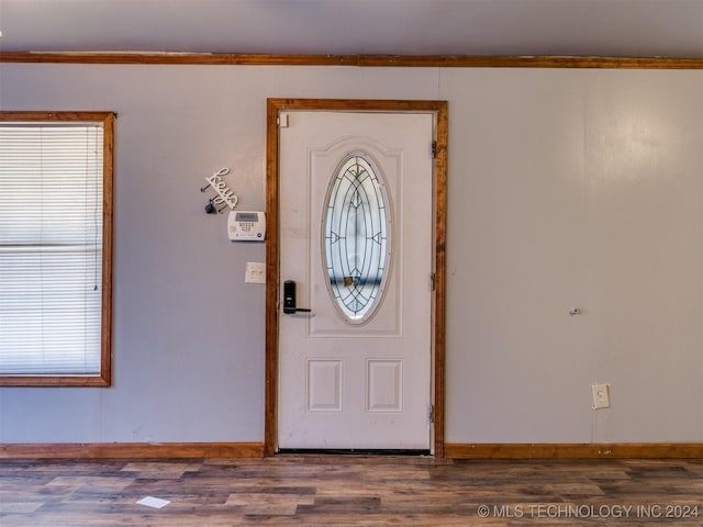 entrance foyer with crown molding and dark wood-type flooring