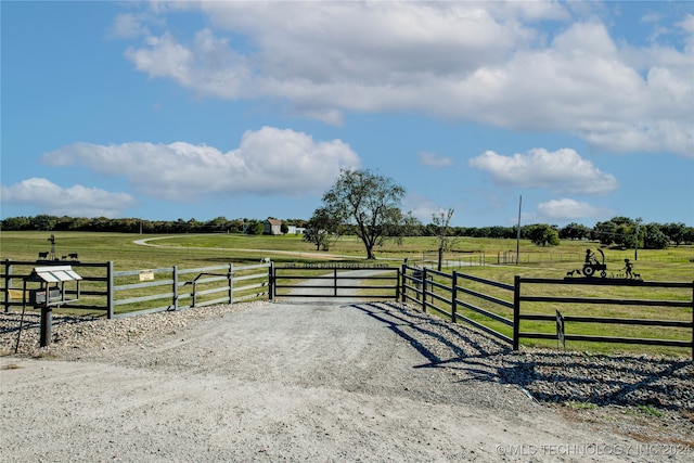 view of gate with a rural view and a yard