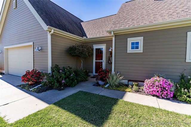 entrance to property featuring a lawn and a garage