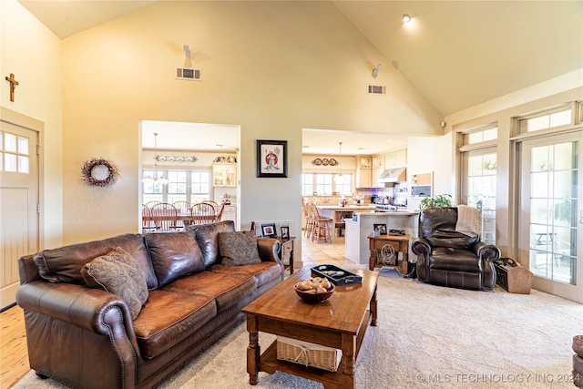 living room with light hardwood / wood-style flooring, a healthy amount of sunlight, and high vaulted ceiling