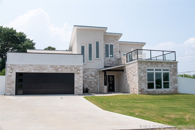 contemporary home with a balcony, a front yard, and a garage