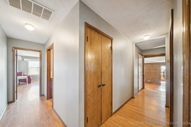 hall featuring light hardwood / wood-style flooring and a textured ceiling