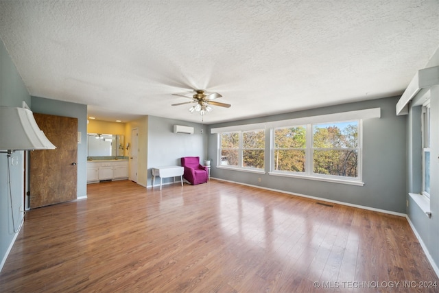 unfurnished room featuring wood-type flooring, a wall mounted air conditioner, ceiling fan, and a textured ceiling