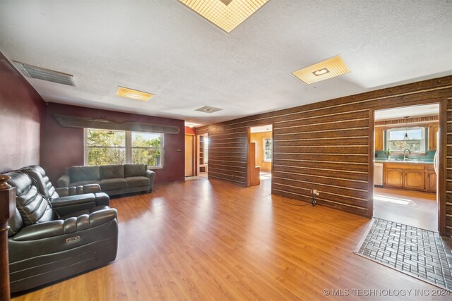 living room featuring wooden walls, wood-type flooring, and a textured ceiling