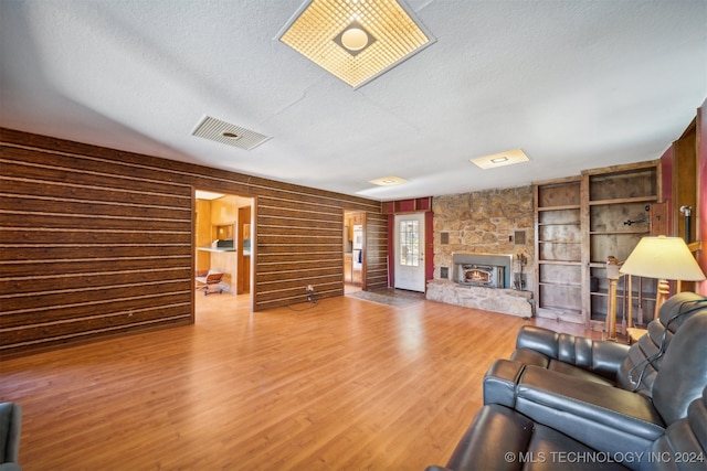 unfurnished living room featuring a fireplace, hardwood / wood-style floors, wood walls, and a textured ceiling