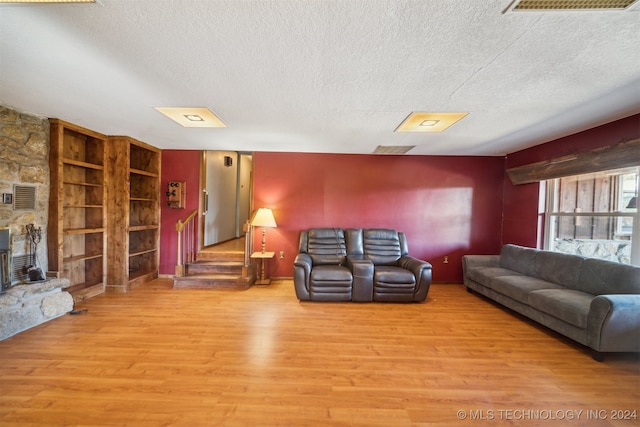 living room featuring a textured ceiling, light hardwood / wood-style floors, and a fireplace