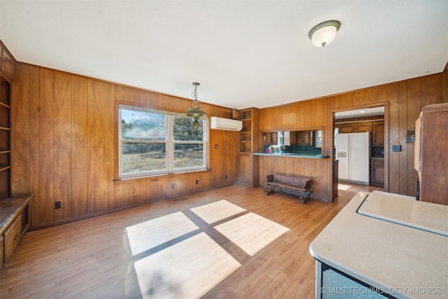 interior space featuring light hardwood / wood-style floors, wood walls, an AC wall unit, and built in features