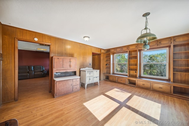 kitchen with pendant lighting, light hardwood / wood-style flooring, wooden walls, and built in shelves