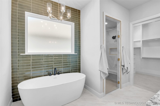 bathroom with shower with separate bathtub, an inviting chandelier, and tile walls