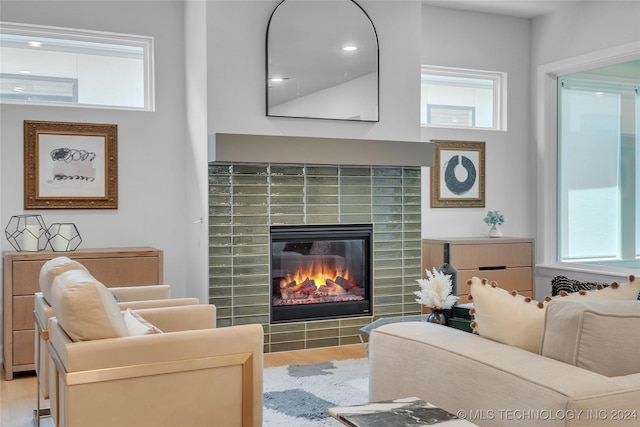 living room with a tile fireplace, a healthy amount of sunlight, and light hardwood / wood-style floors