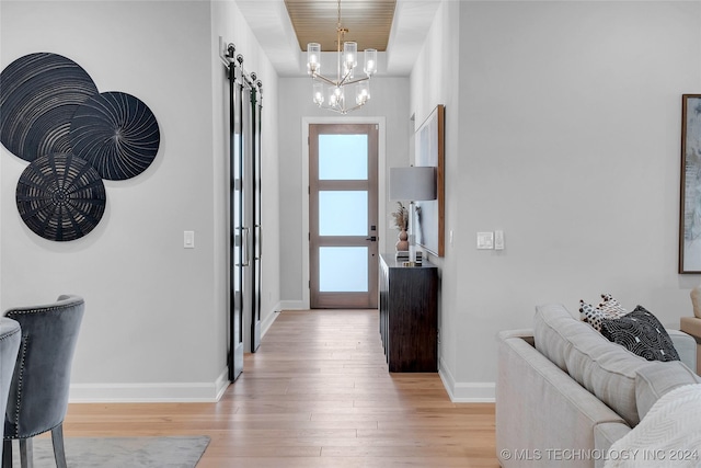 foyer with a barn door, an inviting chandelier, and light wood-type flooring