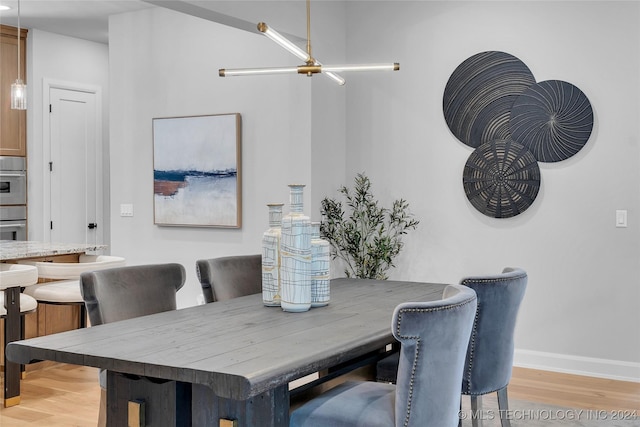 dining area with light hardwood / wood-style flooring and a notable chandelier