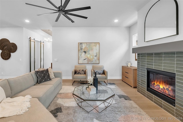 living room with a tile fireplace, ceiling fan, and light hardwood / wood-style flooring