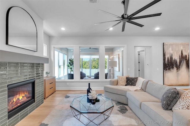 living room with ceiling fan, light hardwood / wood-style floors, and a brick fireplace