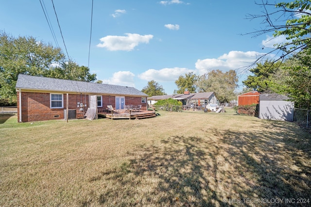 back of property with a shed, a wooden deck, and a lawn