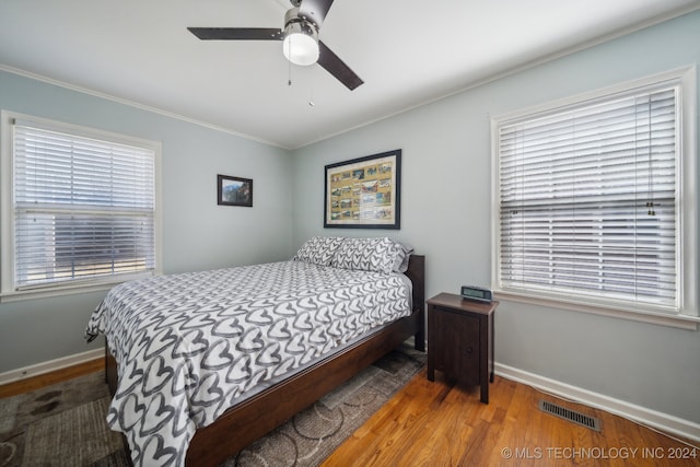 bedroom featuring crown molding, hardwood / wood-style flooring, multiple windows, and ceiling fan