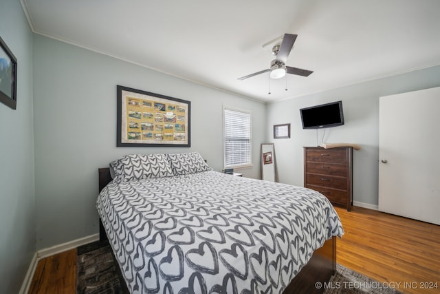 bedroom with ornamental molding, dark wood-type flooring, and ceiling fan