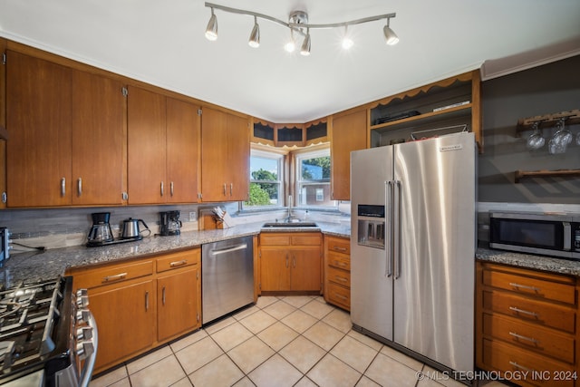 kitchen featuring stone countertops, sink, light tile patterned floors, appliances with stainless steel finishes, and tasteful backsplash