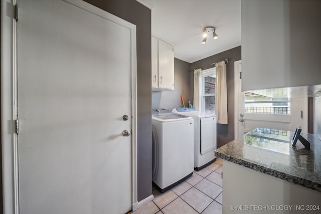 laundry room featuring washing machine and dryer, cabinets, and light tile patterned floors