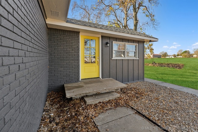 view of exterior entry featuring a lawn