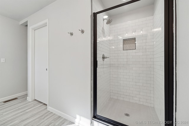 bathroom with hardwood / wood-style flooring and a shower with shower door