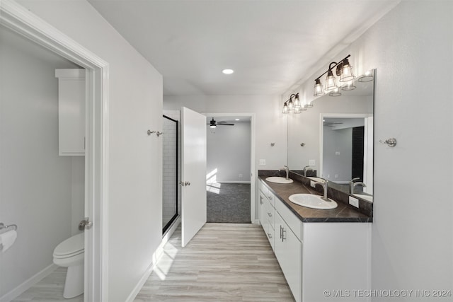 bathroom featuring walk in shower, ceiling fan, vanity, and toilet