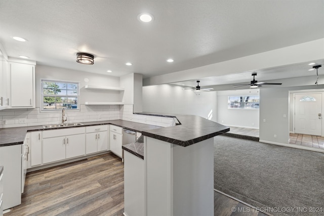 kitchen featuring backsplash, kitchen peninsula, sink, and white cabinets