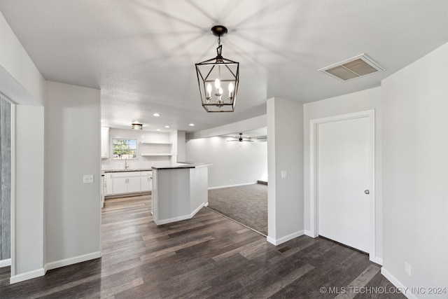 interior space with decorative light fixtures, white cabinetry, sink, dark hardwood / wood-style flooring, and an inviting chandelier