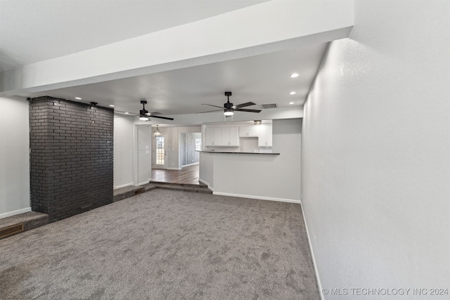 unfurnished living room featuring ceiling fan and carpet flooring