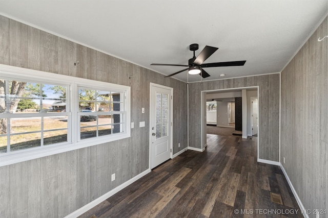 entryway featuring dark wood-type flooring, ceiling fan, and wood walls