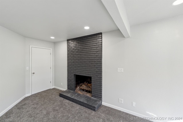 unfurnished living room with carpet flooring, beam ceiling, and a brick fireplace