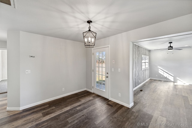 unfurnished dining area with dark wood-type flooring and ceiling fan with notable chandelier