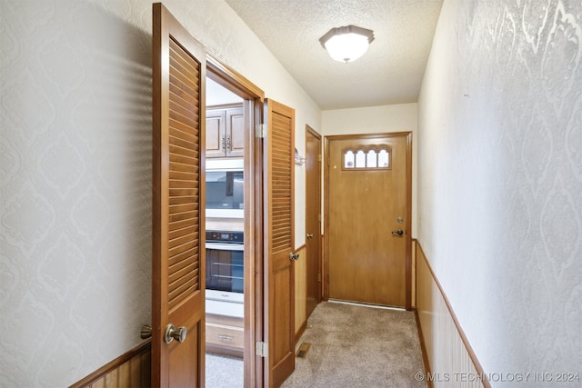 entryway featuring light carpet and a textured ceiling