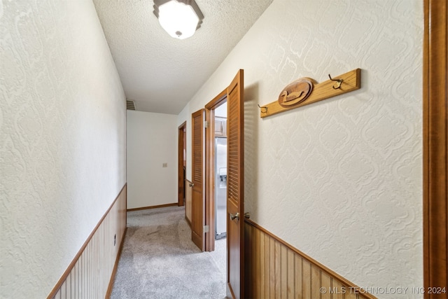 hallway featuring light carpet and a textured ceiling