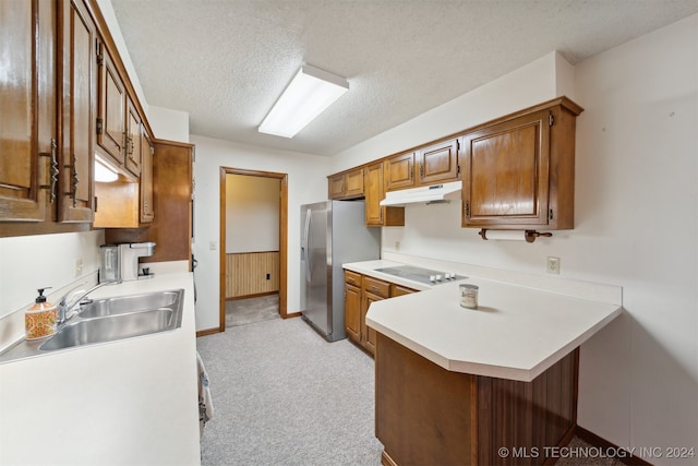 kitchen with sink, a textured ceiling, kitchen peninsula, stainless steel fridge, and light colored carpet