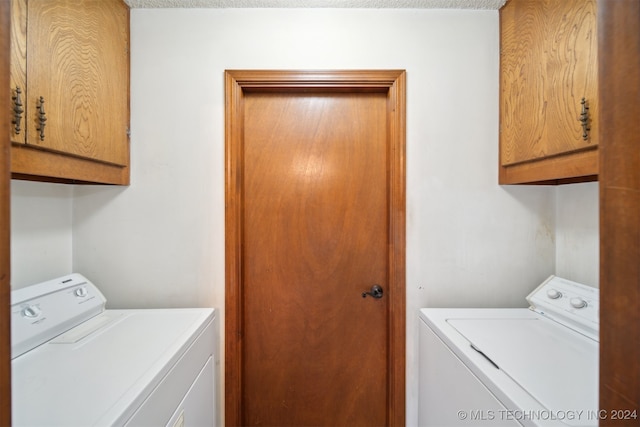 clothes washing area with a textured ceiling, cabinets, and washing machine and clothes dryer