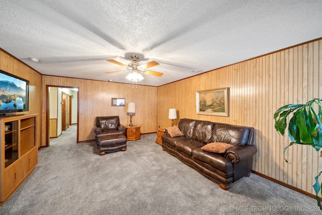 carpeted living room with wooden walls, a textured ceiling, and ceiling fan