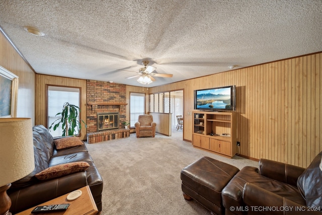 carpeted living room with wooden walls, a textured ceiling, a brick fireplace, and ceiling fan